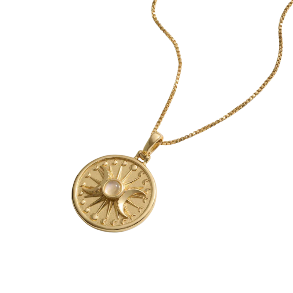Gold necklace with a circular pendant featuring a sun, moon, and a central pink gemstone.