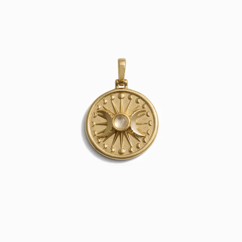 Gold circular pendant with a triple moon goddess symbol and a light-colored gemstone at its center.