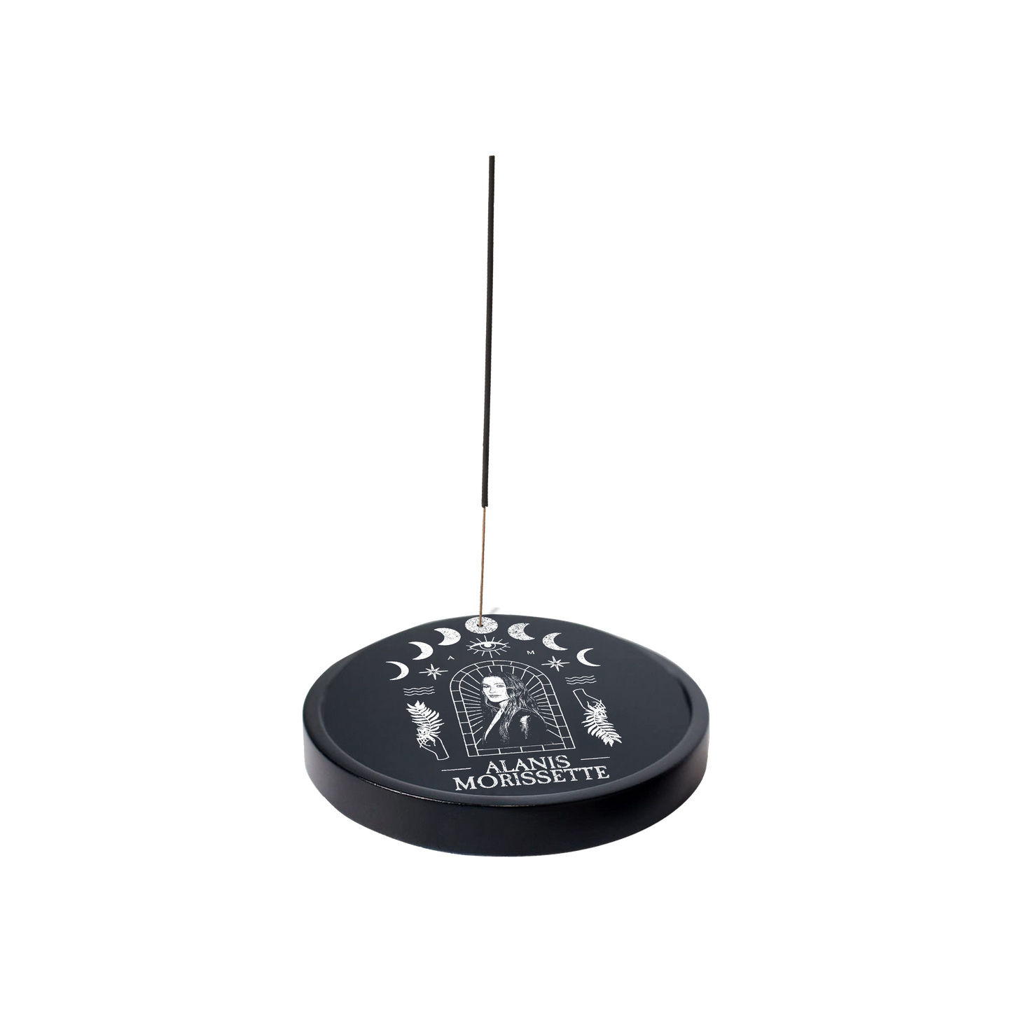 Circular incense holder with celestial designs and ’Alanis Morissette’ text, featuring a thin incense stick.