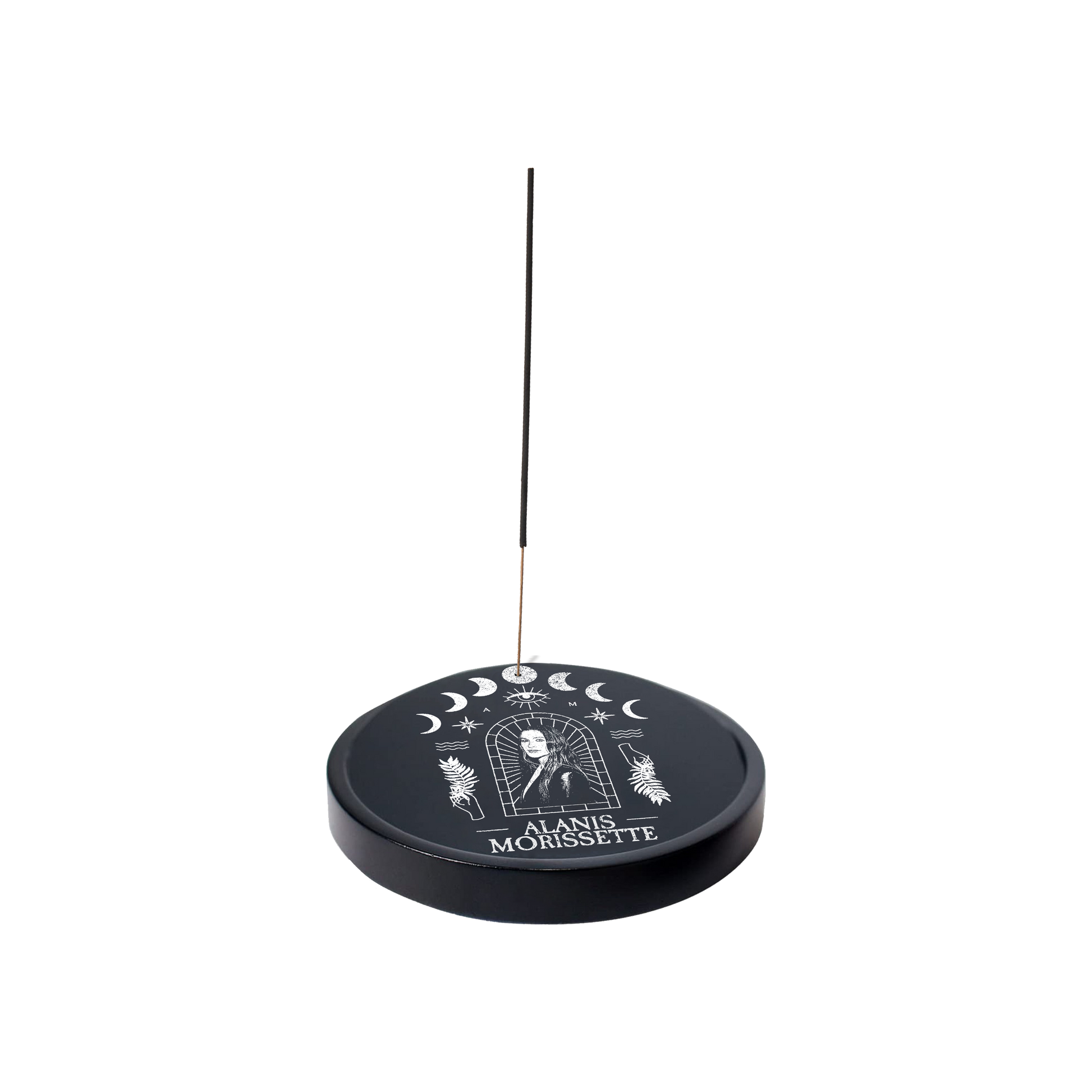 Circular incense holder with celestial designs and ’Alanis Morissette’ text, featuring a thin incense stick.